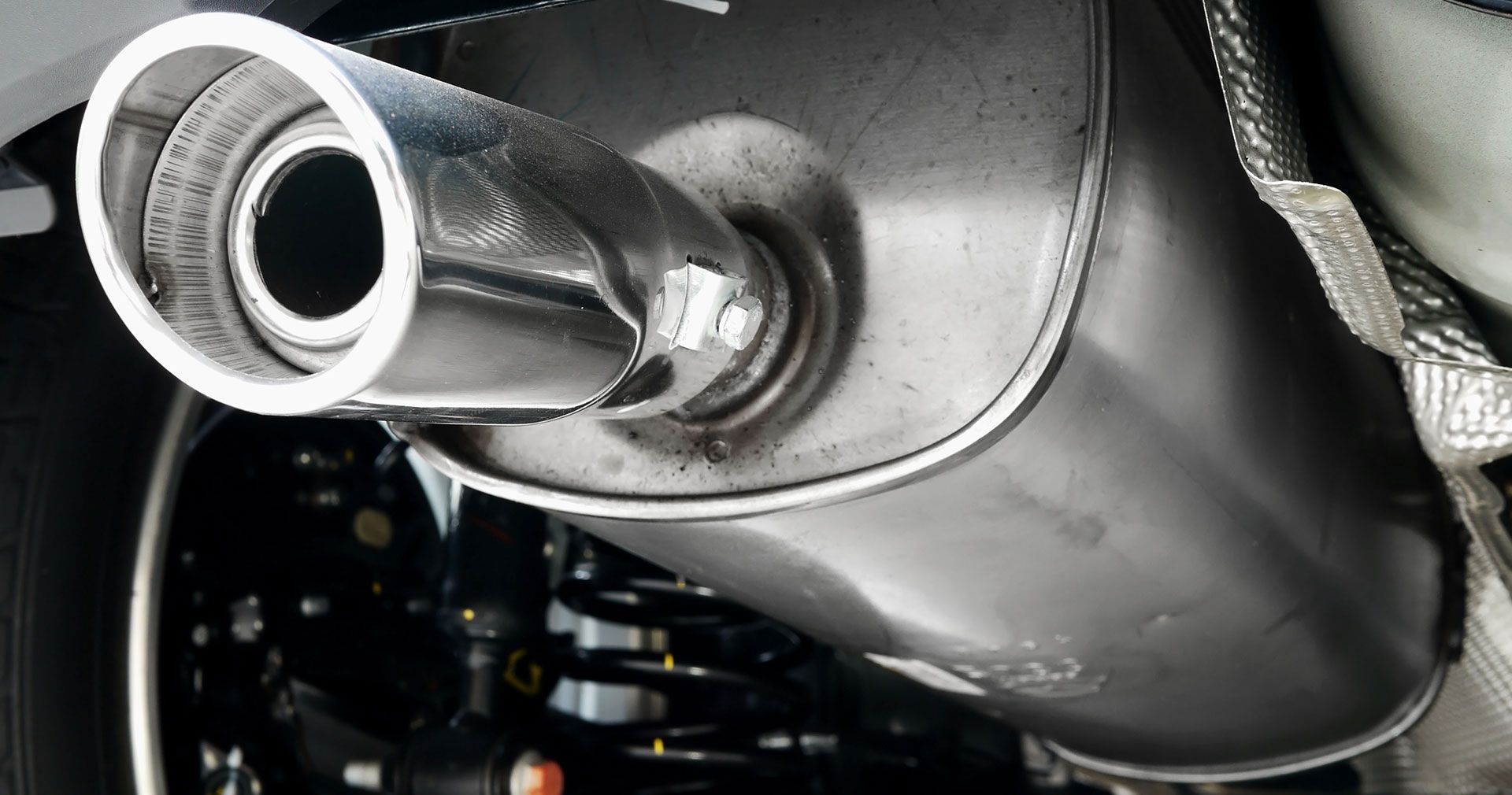 Close-up of a car’s chrome exhaust pipe and muffler under the vehicle