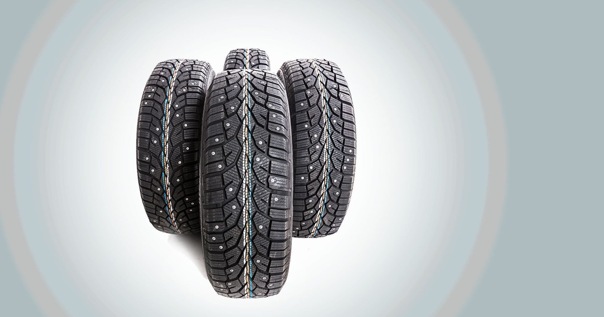 Four black tires stacked together on a light gray background