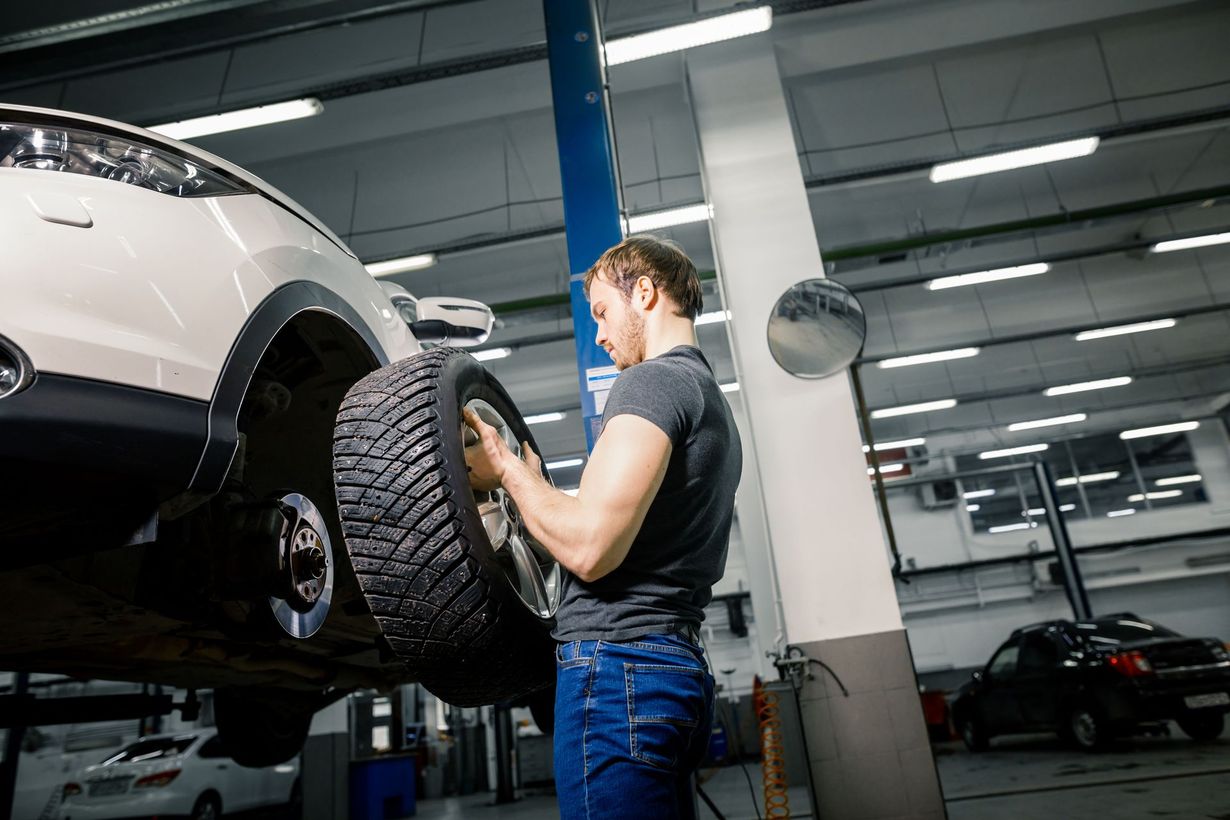 Mechanic inspecting the wheel of a lifted SUV in a garage