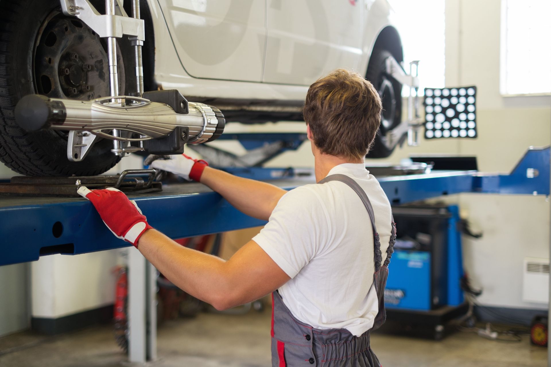 Mechanic inspecting a car’s undercarriage on a lift in a bright auto shop
