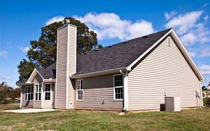 The back of a house with a chimney on the roof.