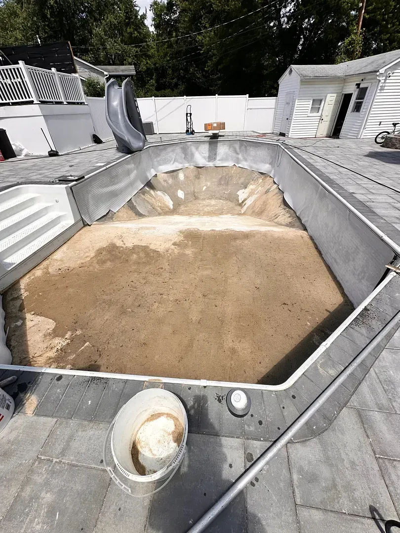 Empty octagonal rooftop pool under construction, with exposed dirt center and gray concrete edges