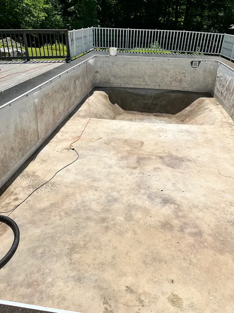 Empty concrete pool under construction with white railings and a shallow recessed section