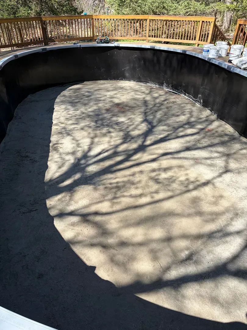 Empty concrete skate bowl with tree shadows and a wooden railing in the background