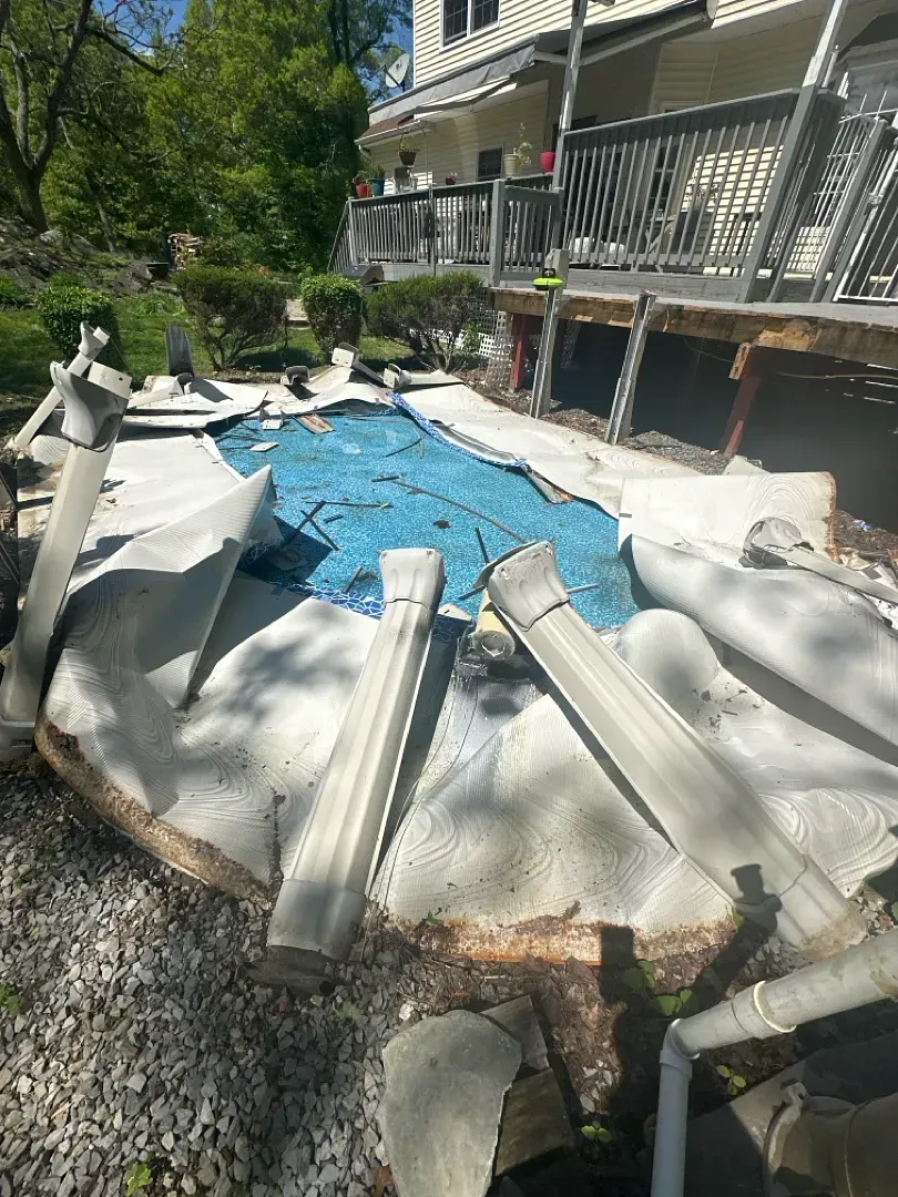 Backyard pool covered in torn white debris, with blue water visible through the center.