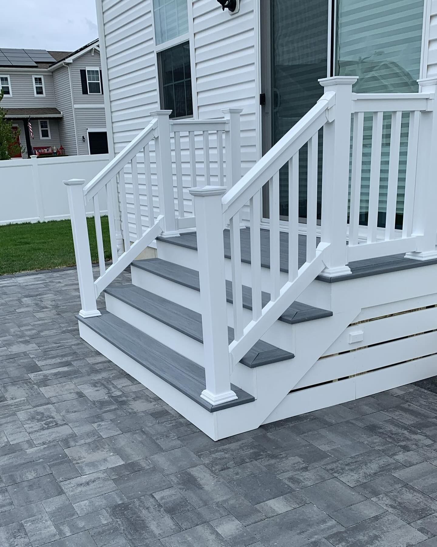 A white porch with gray steps and a white railing