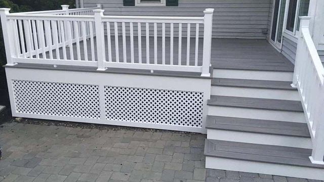 A white deck with stairs leading up to it and a white railing.