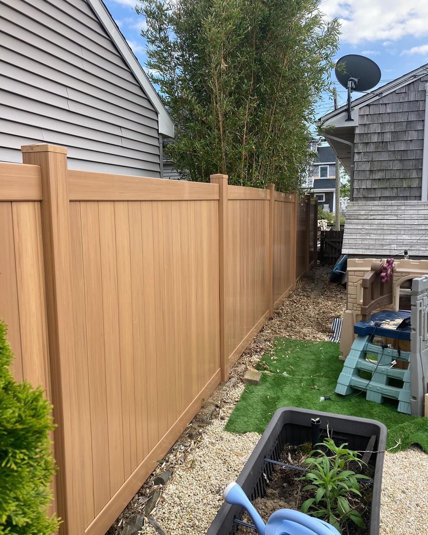 A wooden fence is in the backyard of a house.