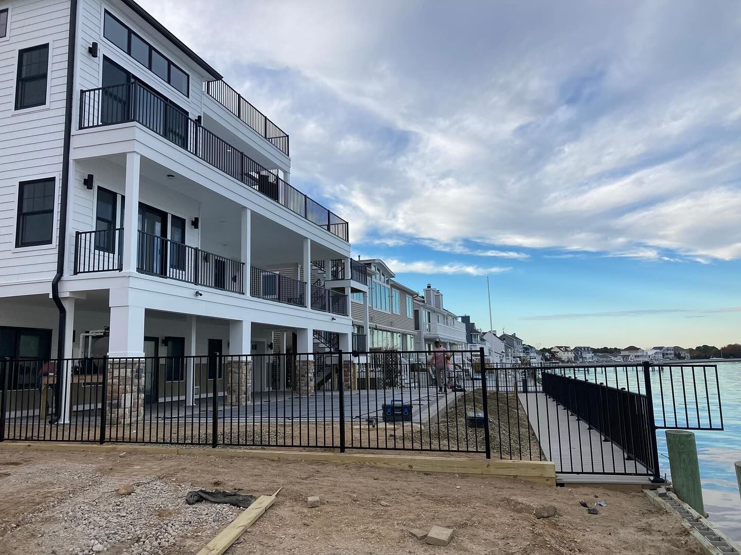 A large white building with a fence around it is next to a body of water.