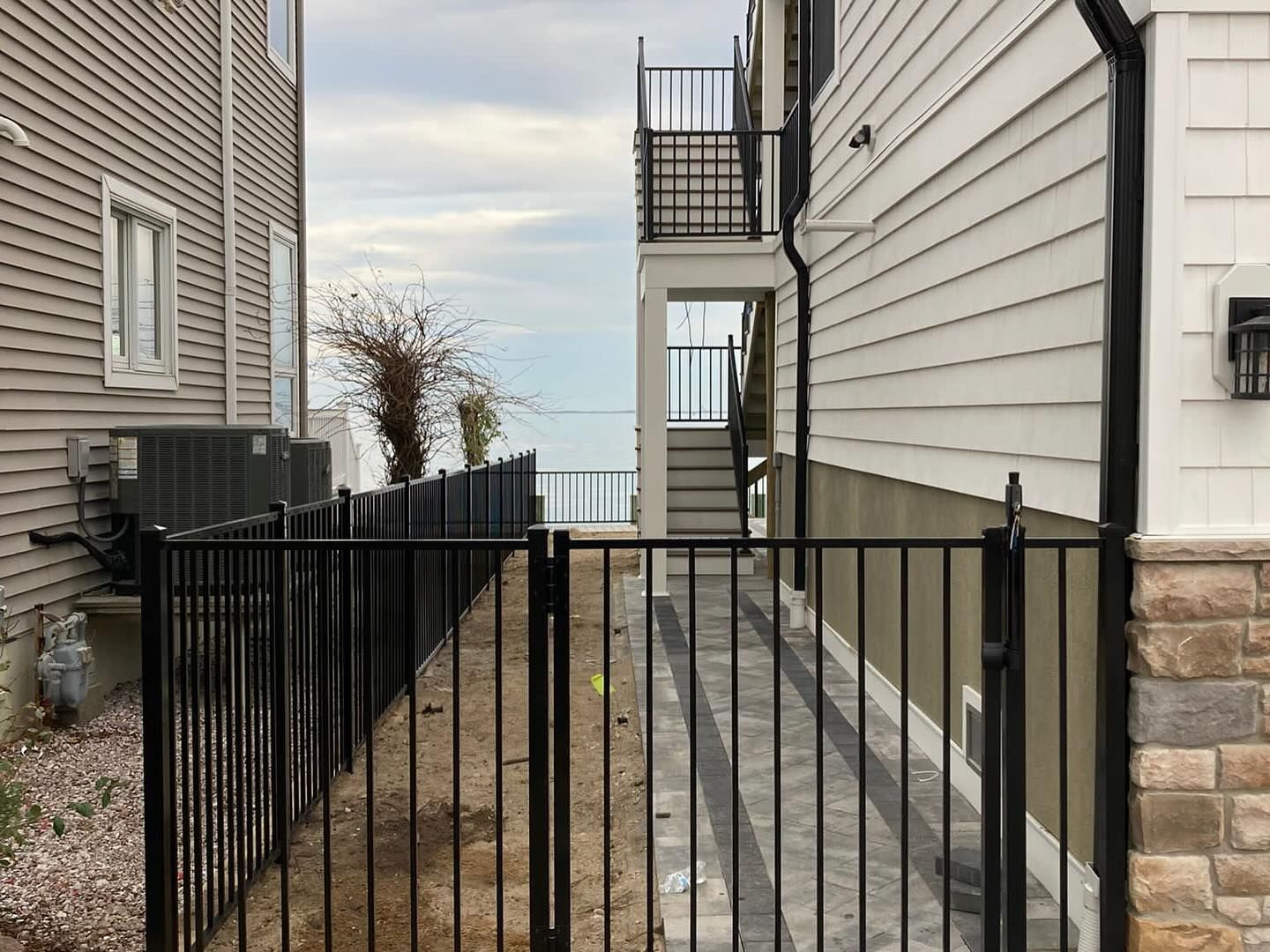 A fence between two houses with stairs leading up to the second floor.