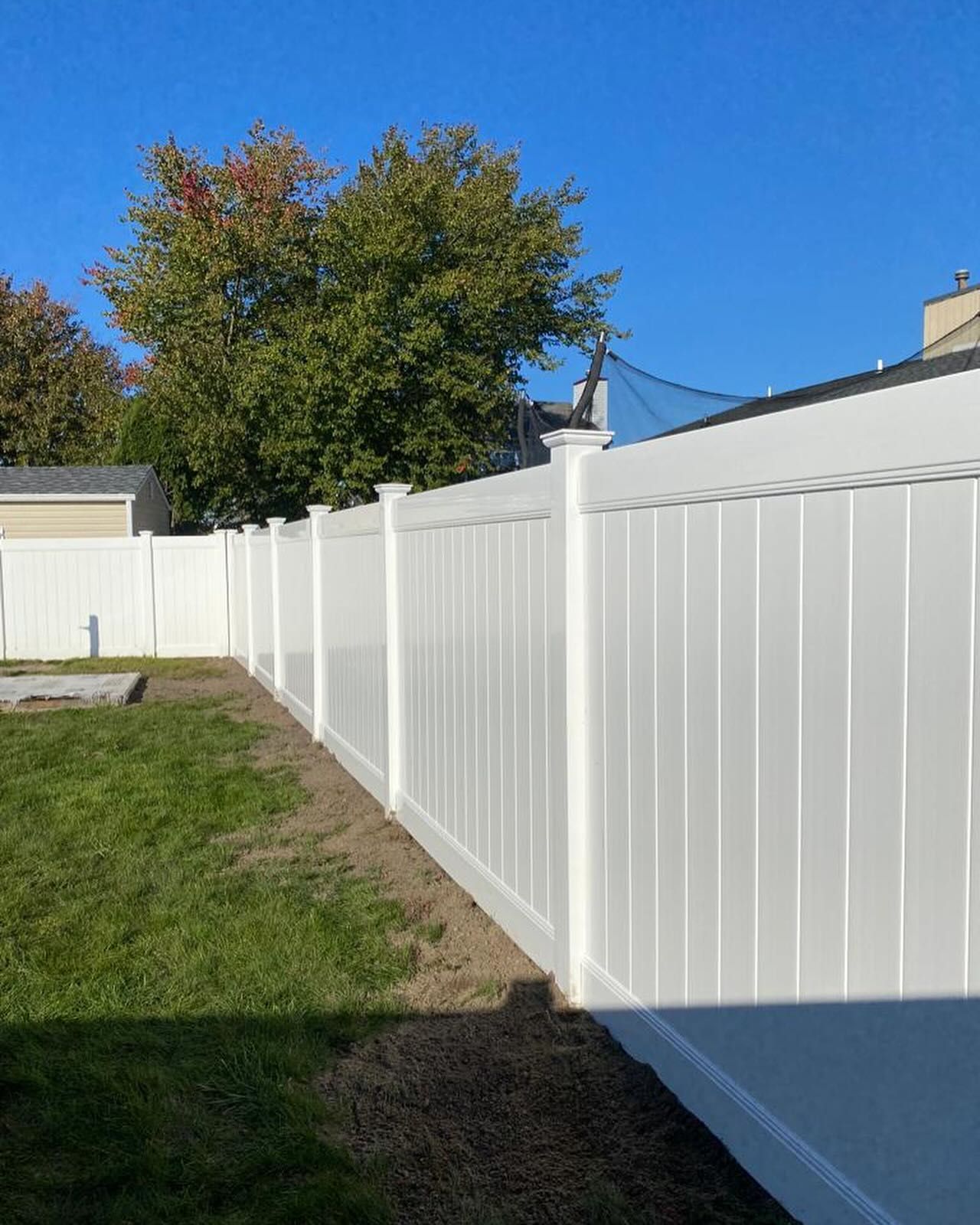 A white fence is surrounding a lush green yard.