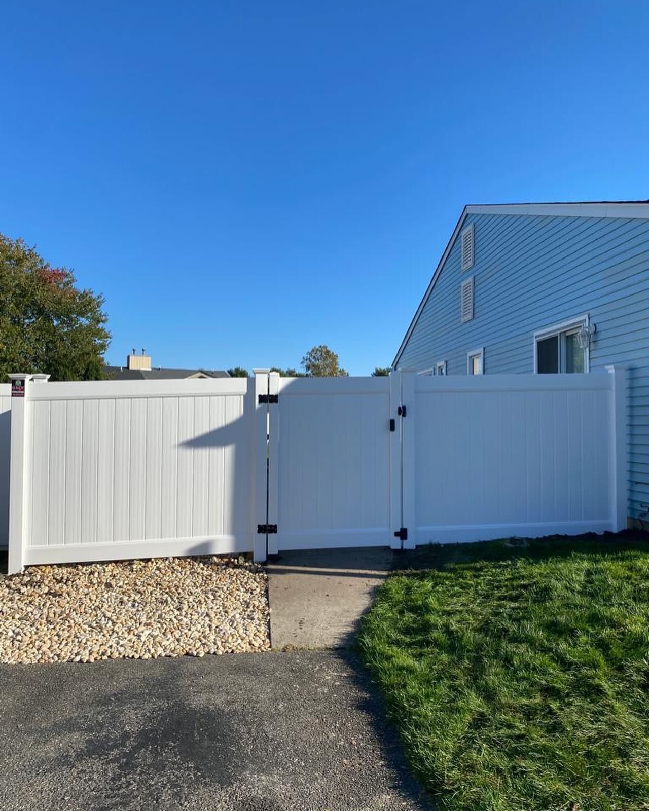 A white fence with a gate in front of a house.