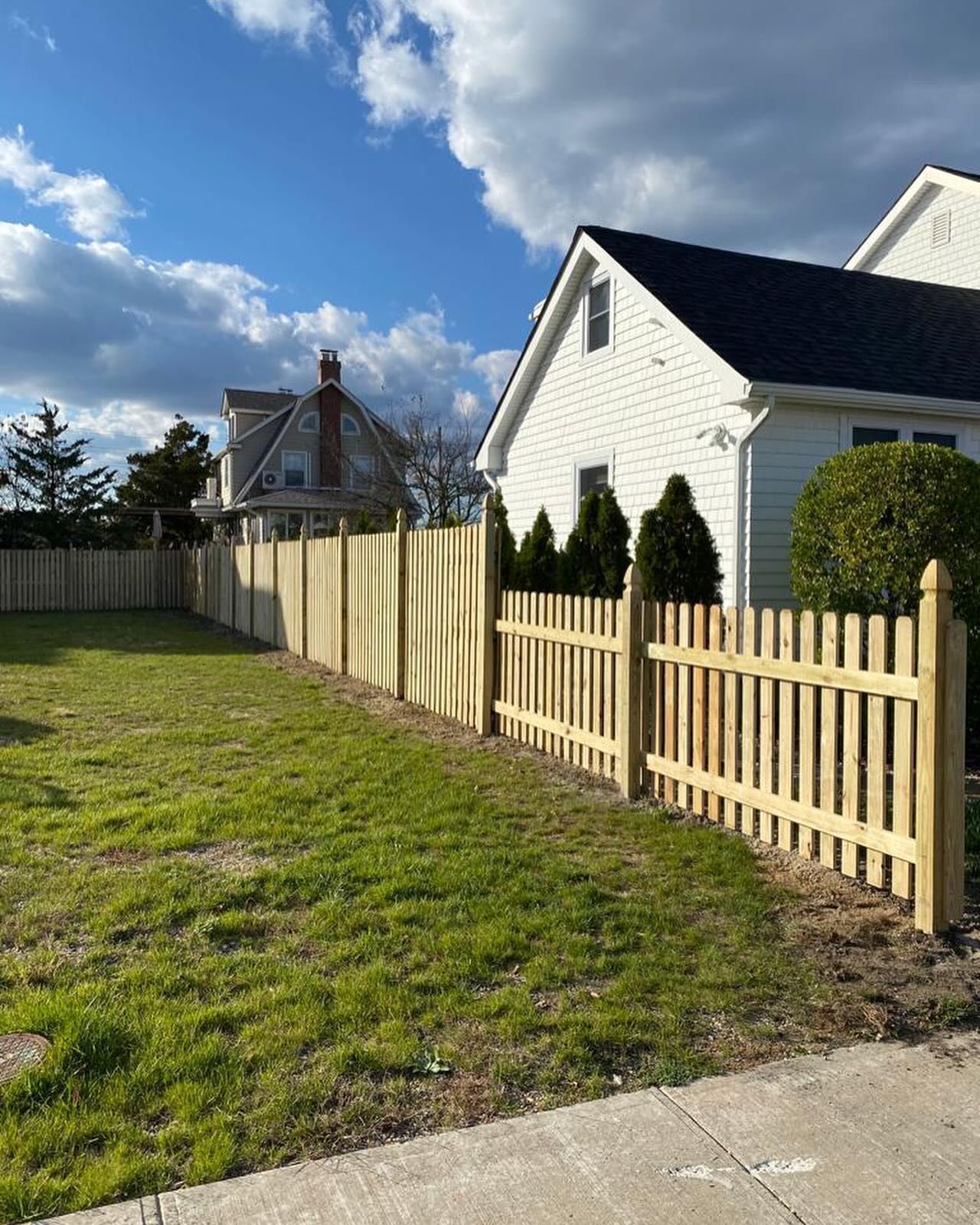 A wooden picket fence is in front of a white house.