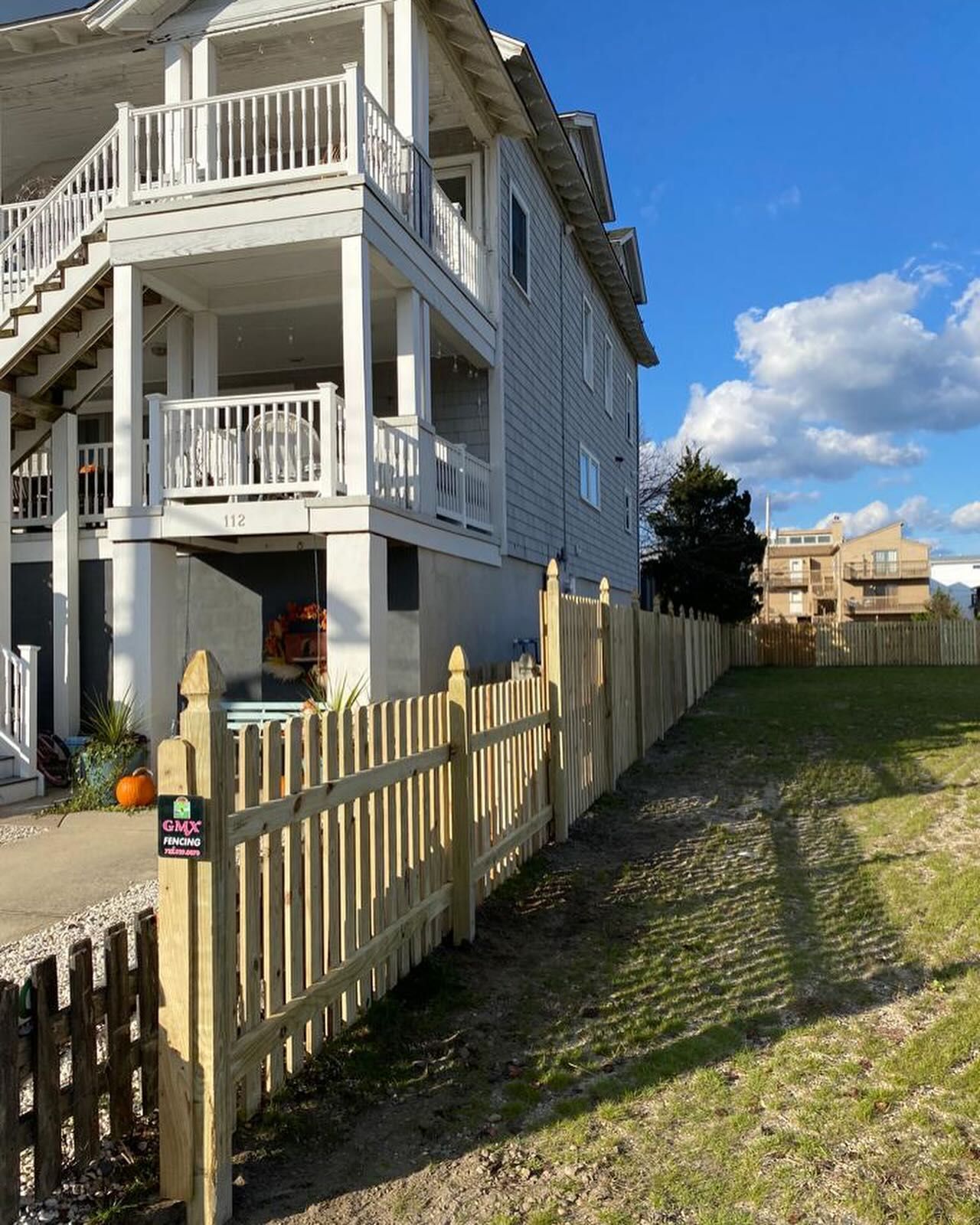 A large white house with a wooden fence in front of it.
