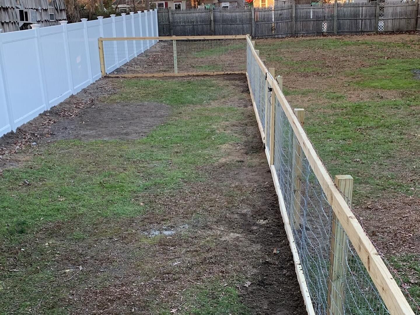 A wooden fence surrounds a lush green field.