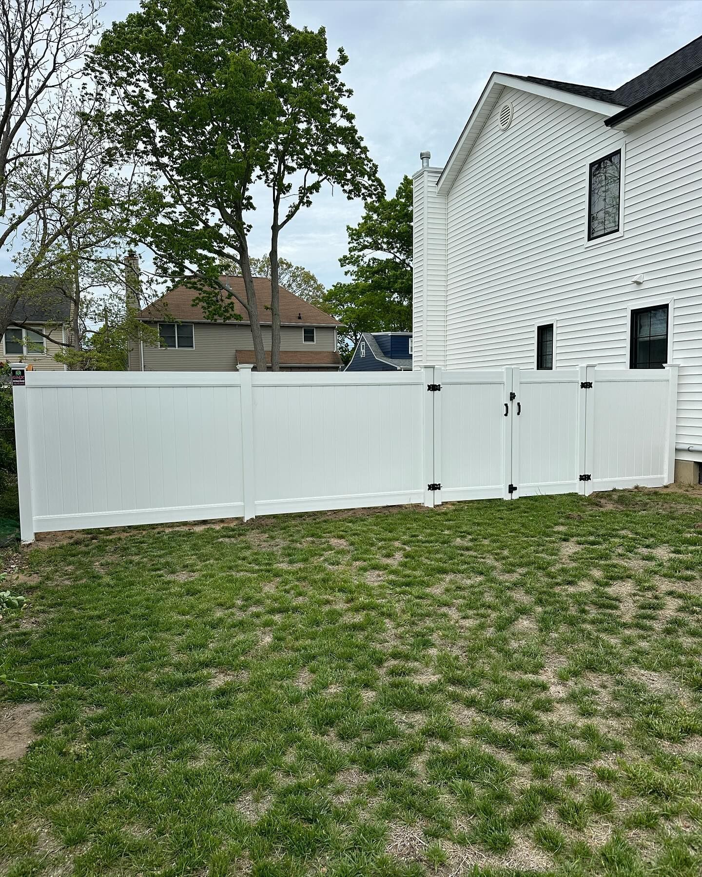 A white fence is in the backyard of a house.
