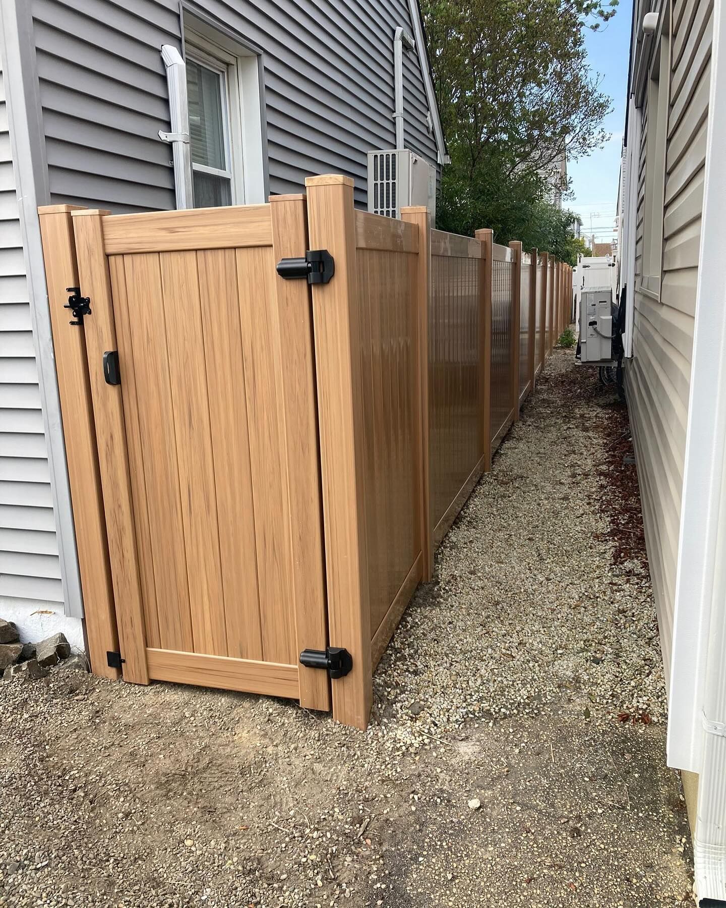 A wooden fence with a gate is next to a house.