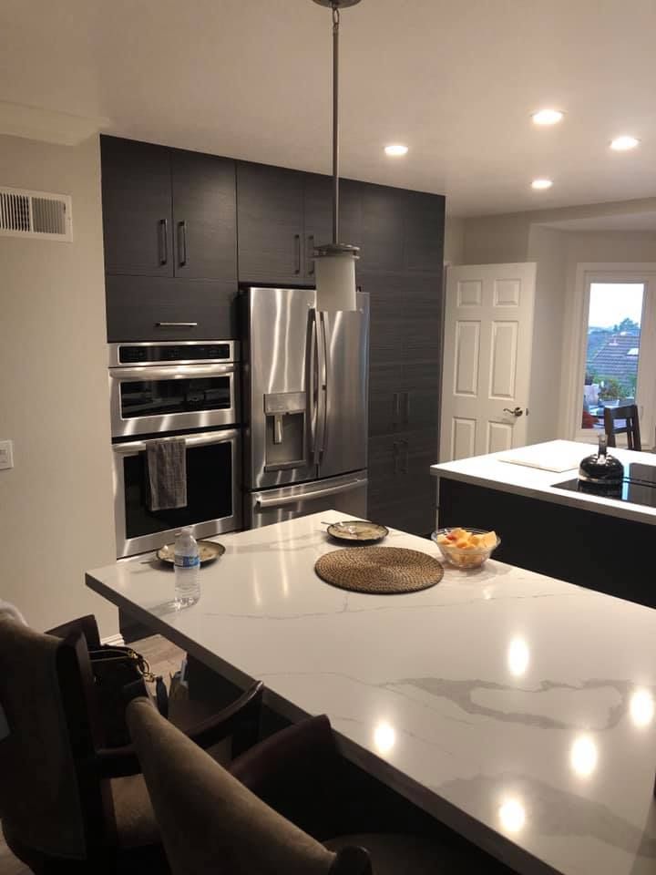 A kitchen with stainless steel appliances and a large island with a table and chairs.