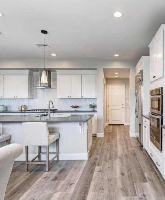 A kitchen with white cabinets and wooden floors