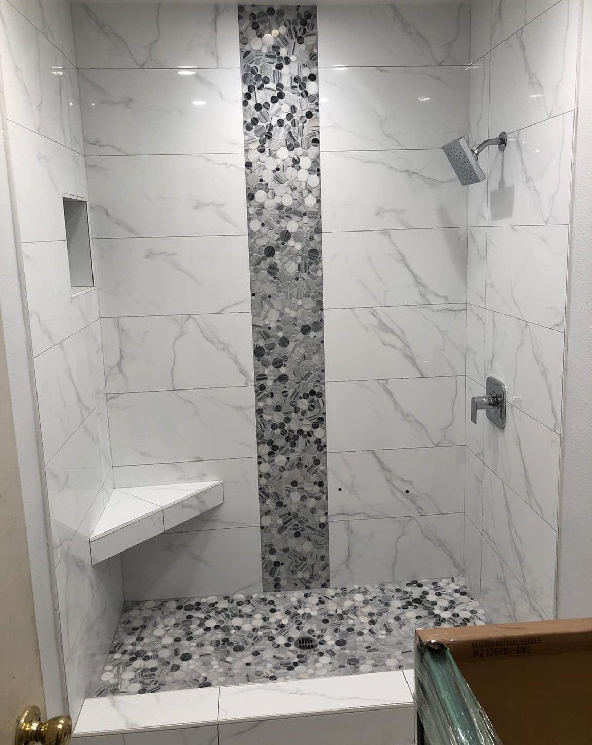 A shower with a bench and a shower head in a bathroom.