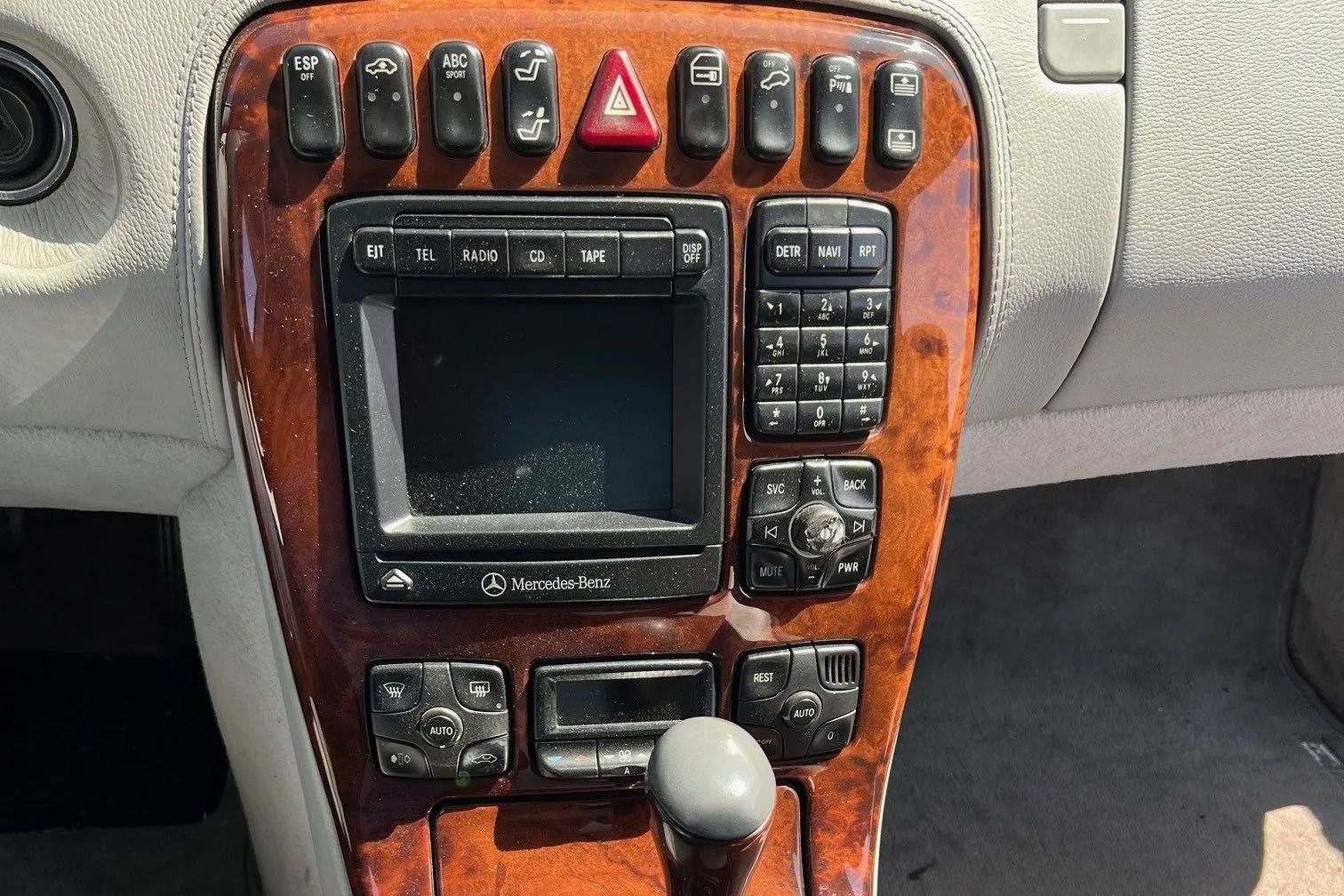 Car dashboard with wood paneling, navigation screen, and various buttons.