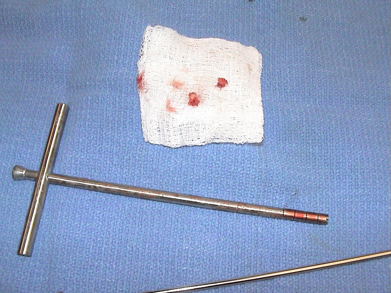 A needle and a piece of tissue on a blue cloth