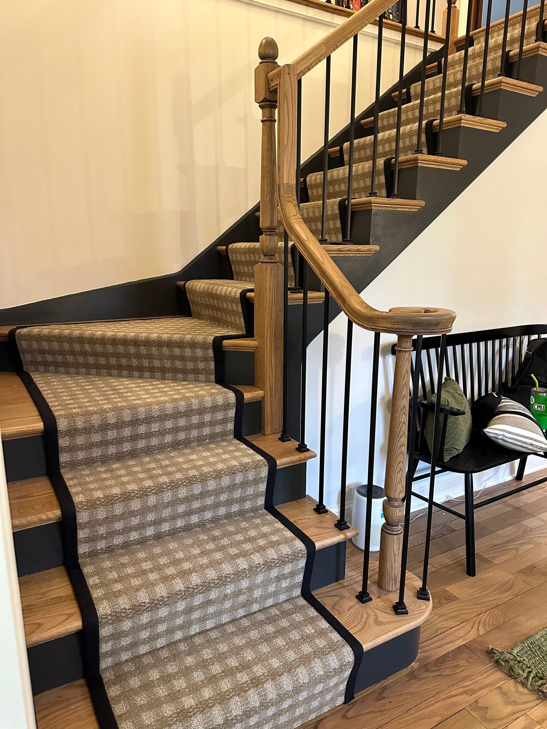 A staircase with a carpet on the steps and a wooden railing