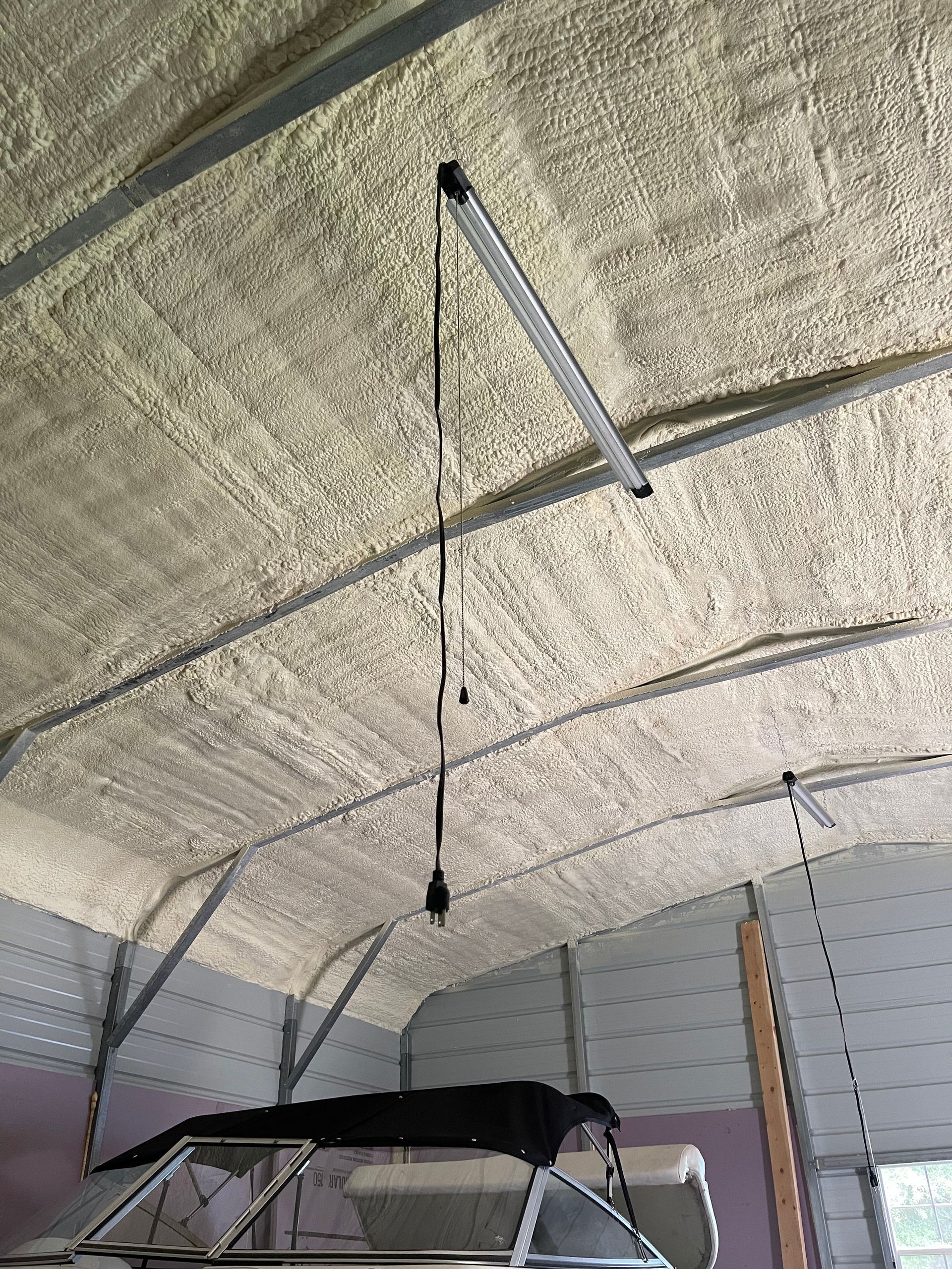 A boat is hanging from the ceiling of a garage.