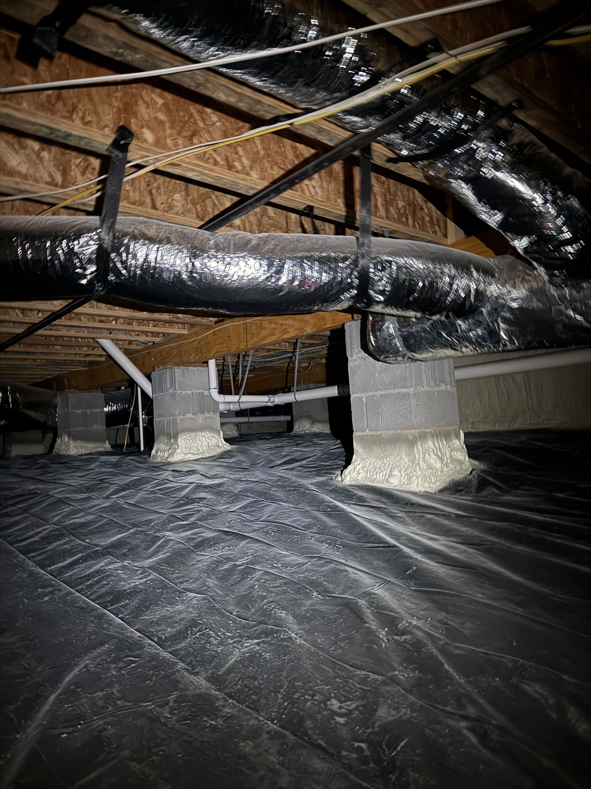 The ceiling of a basement with a lot of pipes coming out of it.