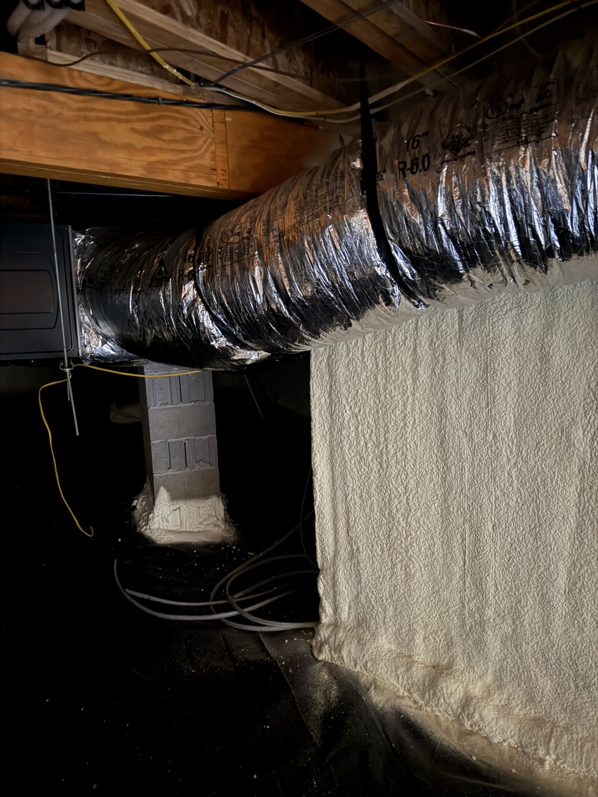 A duct is hanging from the ceiling of a basement.