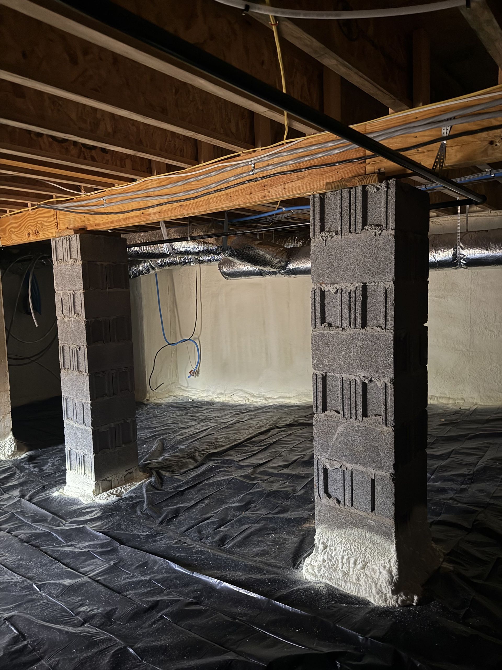 A basement with concrete pillars and a wooden ceiling.