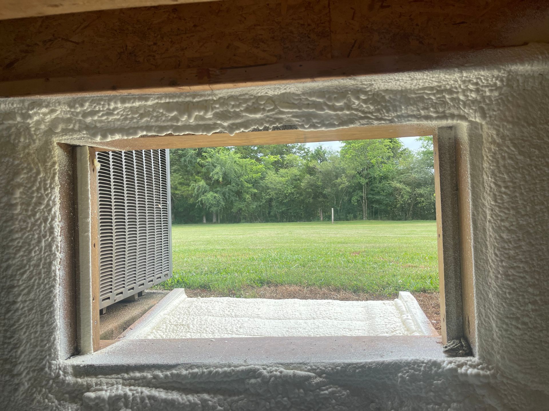 A window in a wall with a view of a field.