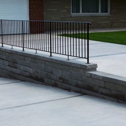 Concrete ramp with black metal railing beside a brick building