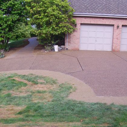 Driveway in front of a garage with a tree, lawn, and curved walkway.