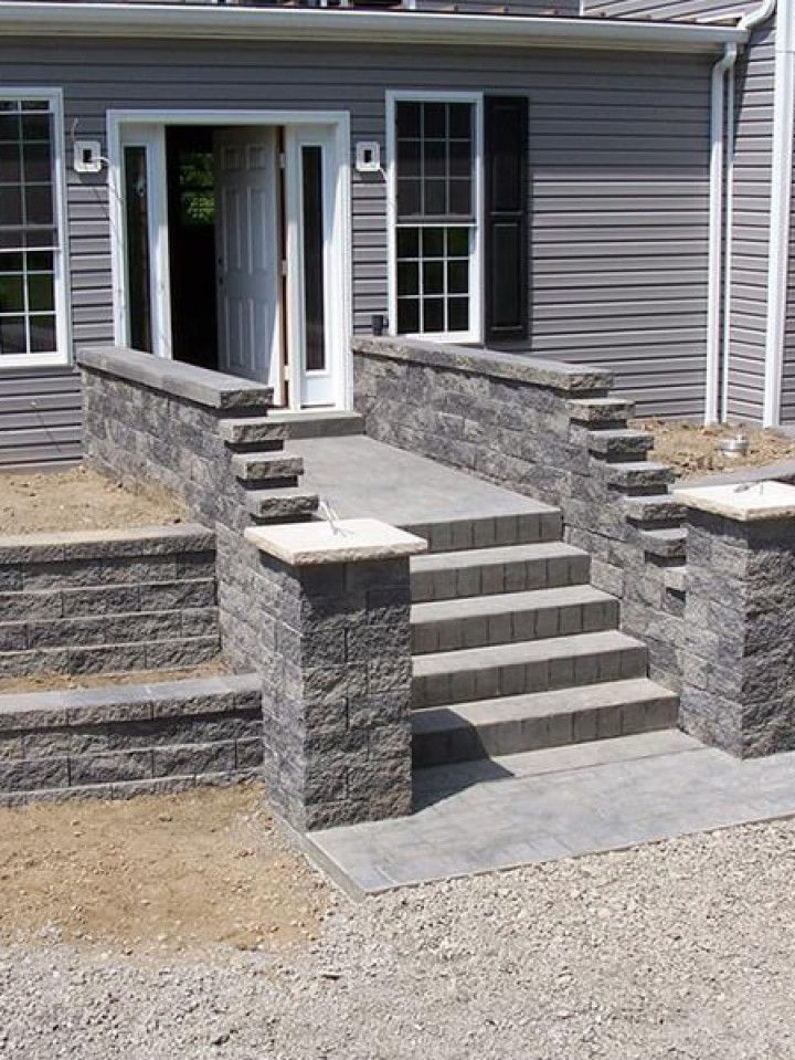 Stone front steps and ramps leading to a house entrance with gray siding.