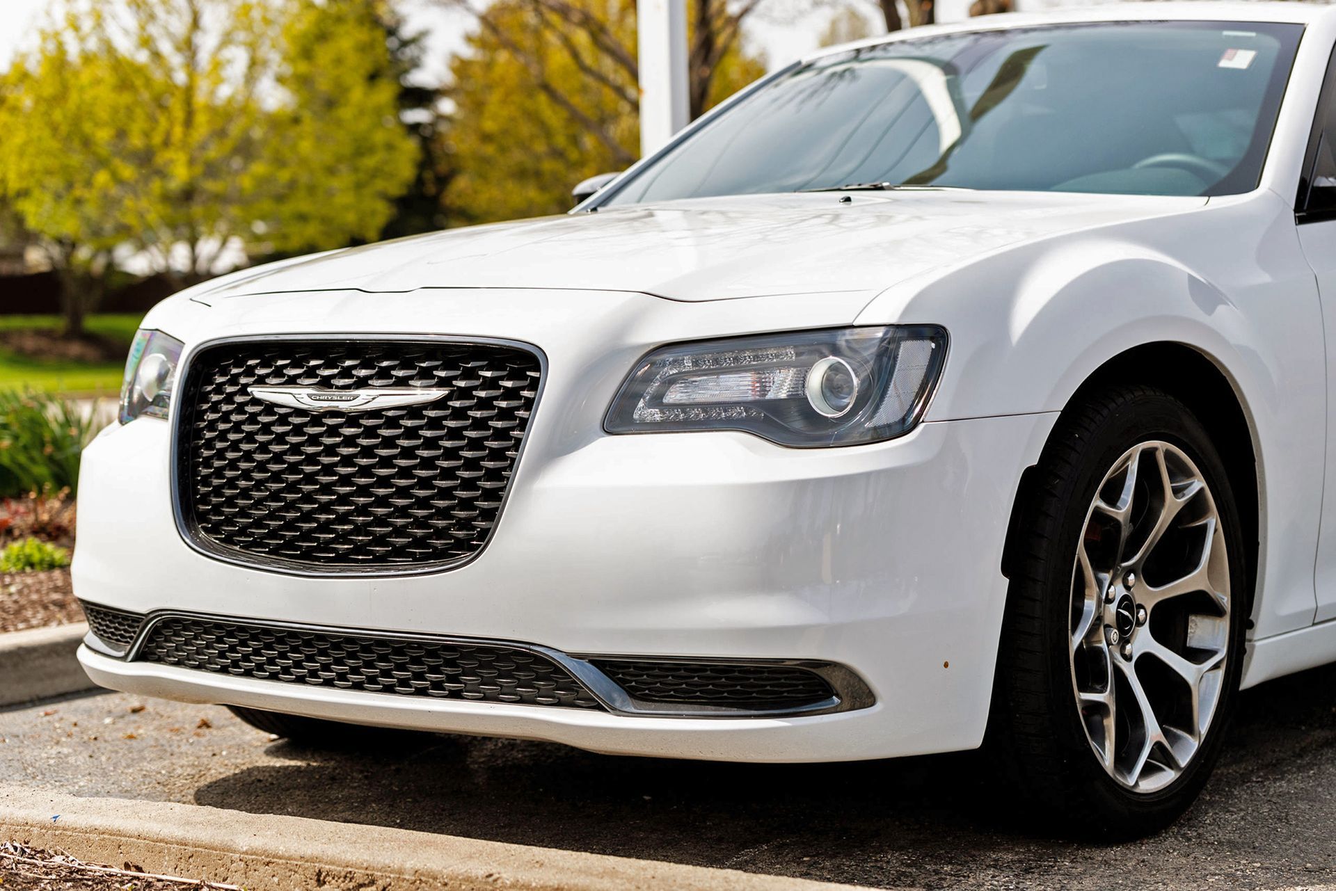 White Chrysler 300 sedan with a black grill parked outdoors.