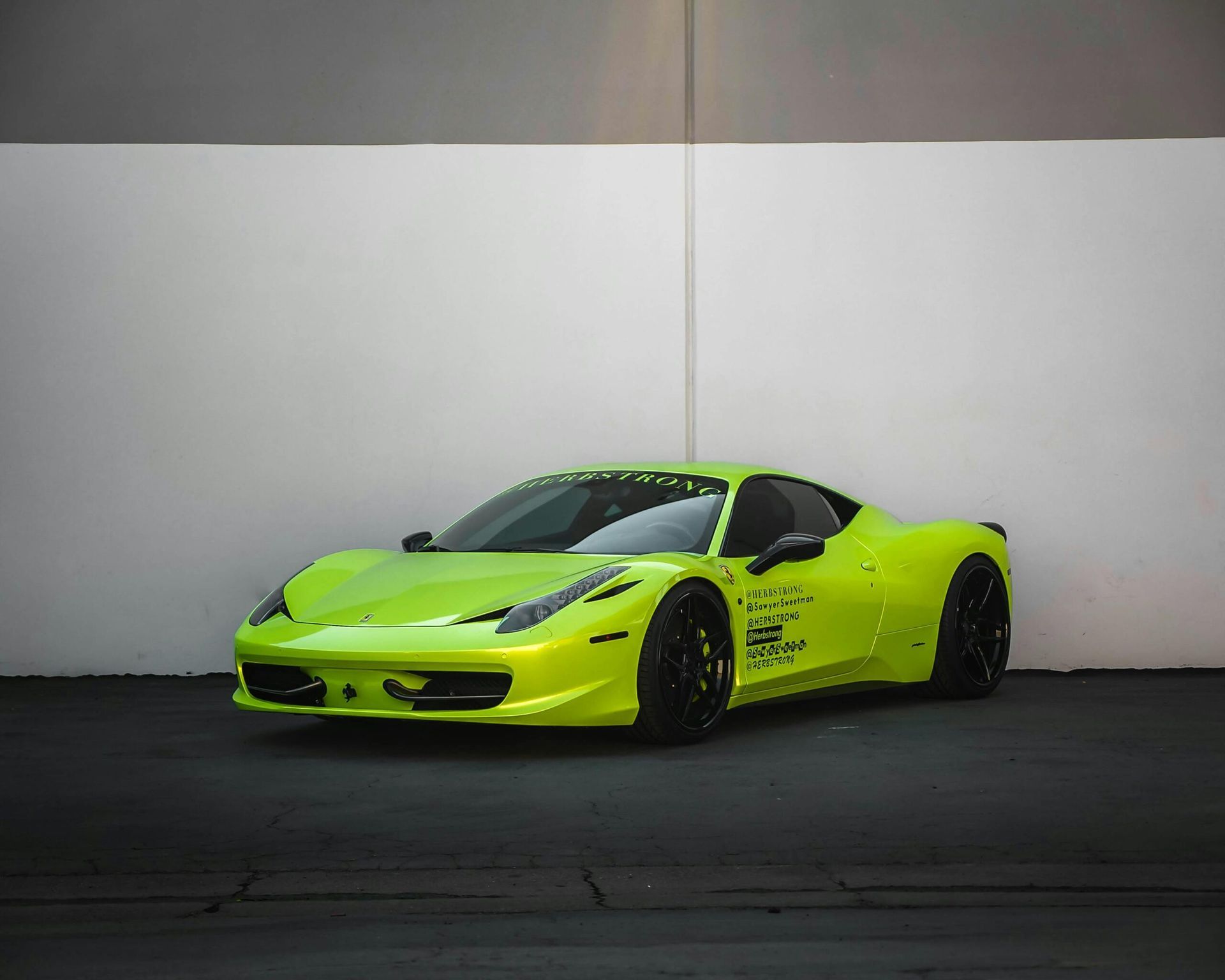 Bright green Ferrari sports car parked on dark surface.