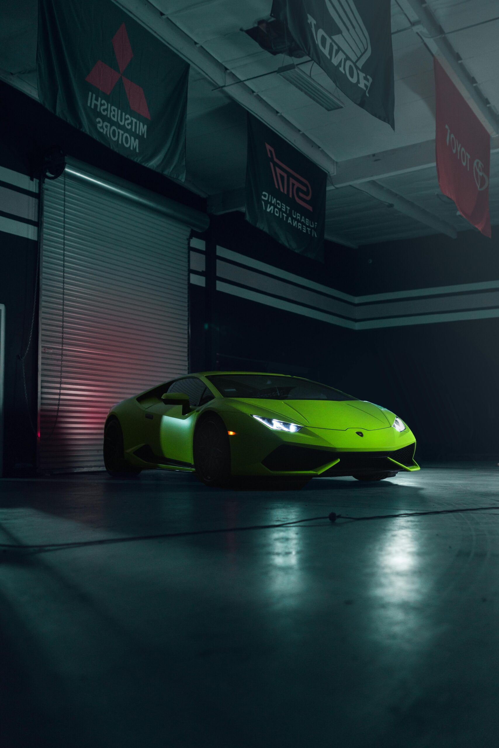 Green Lamborghini in a garage with banners.