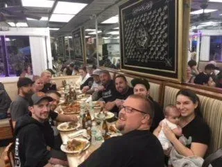 A group of people are sitting at a long table in a restaurant.