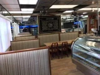 A restaurant with tables and chairs and a display case.