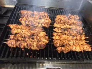 Chicken skewers are cooking on a grill.