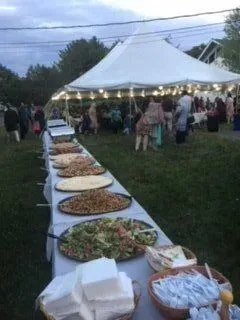 A long table filled with plates of food under a tent.