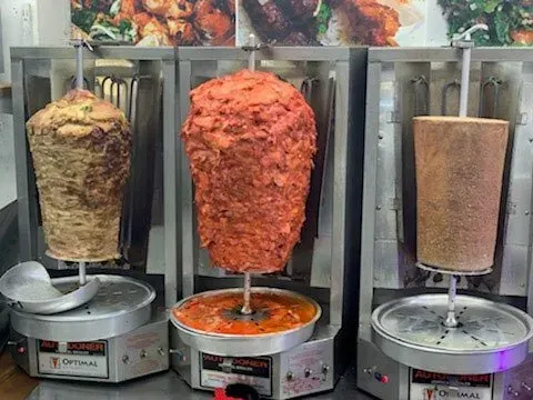 Three kebabs are being cooked on a grill in a restaurant.