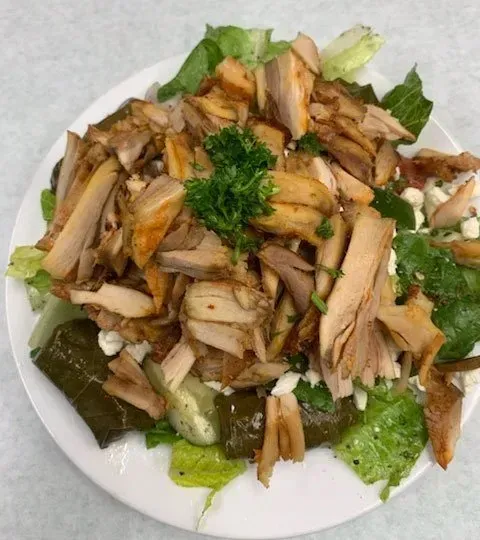 A white plate topped with chicken and lettuce on a table.