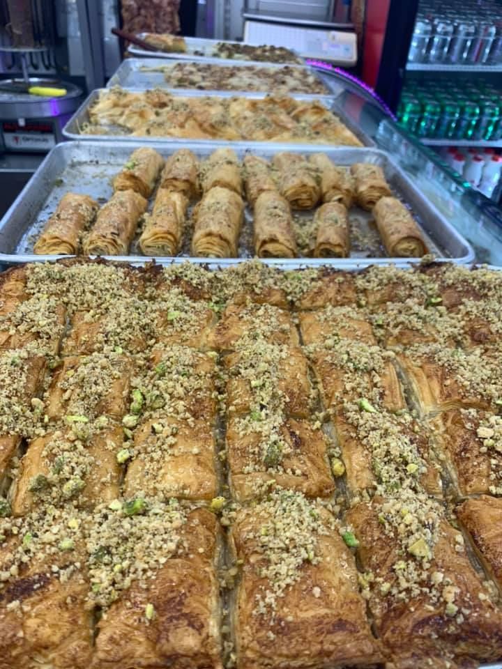 A bunch of trays of food are sitting on top of each other in a bakery.