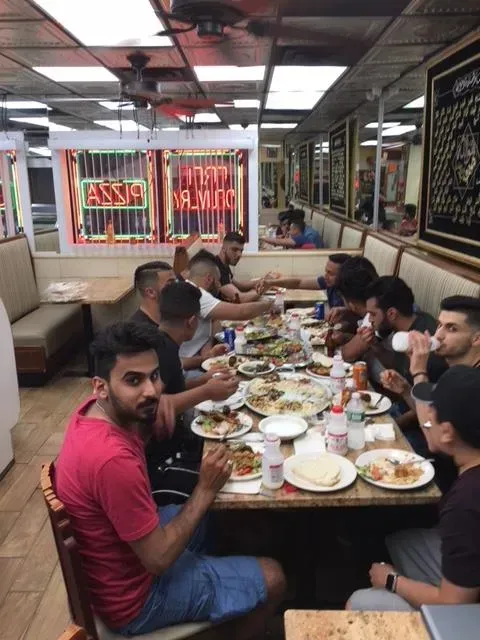 A group of men are sitting at tables in a restaurant eating food.