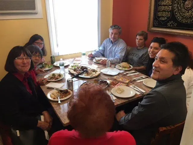A group of people are sitting around a table with plates of food.
