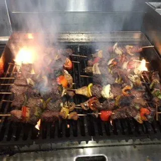 A bunch of meat and vegetables are cooking on a grill.
