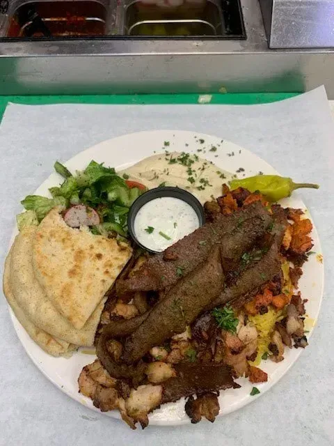 A white plate topped with a variety of food and a dipping sauce.