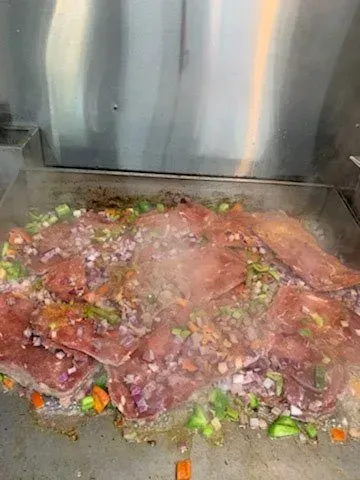 Meat and vegetables are being cooked on a grill.